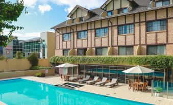 a large hotel with a pool and outdoor seating area , surrounded by chairs and umbrellas at Peppers the Hills Lodge