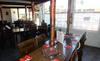 a restaurant with wooden tables and chairs , a pipe fan in the center , and red place cards on each table at Jacksons Motor Inn