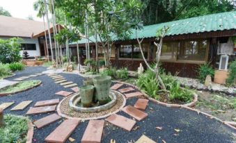 a courtyard surrounded by trees and plants , with a fountain in the middle of the yard at Suanpa Resort