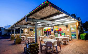an outdoor dining area with several tables and chairs , as well as a variety of toys and decorations at BIG4 Happy Hallidays