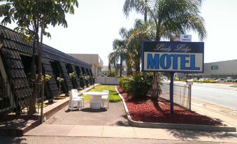 "a motel with a sign that says "" lady gladys motel "" and a white chair in front of it" at Lindy Lodge Motel