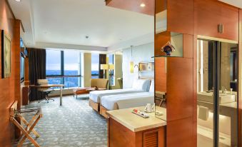 The room is spacious and includes a bed, desk, and a window with a view of the ocean in an open concept living area at Swissotel Foshan Guangdong