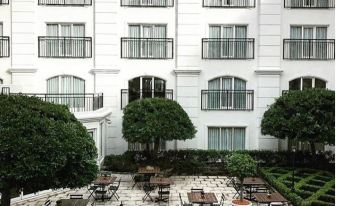 a large white building with multiple balconies , surrounded by trees and a courtyard filled with potted plants at InterContinental Sydney Double Bay