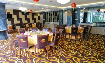 a large banquet hall with multiple round tables set for a formal event , featuring gold and black decorations at Pakons Prime Hotel