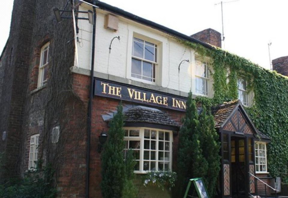 "a brick building with a sign that reads "" the village inn "" prominently displayed on the front" at The Village Inn