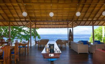 a wooden deck overlooking the ocean , with a dining table and chairs set up for a meal at Sali Bay Resort
