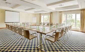 a conference room set up for a meeting , with chairs arranged in rows and a projector on the wall at Vila Vita Parc