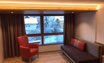 a cozy living room with wooden floors , red couches , and a window offering a view of snow - covered trees at Hotel Park