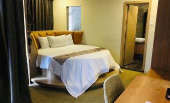 The bedroom features a large bed and a table in the middle, with an enclosed area beside it at Izumi Hotel Bukit Bintang Kuala Lumpur