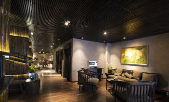 a modern lounge area with wooden floors , black walls , and furniture , including couches and chairs at Cochin Zen Hotel