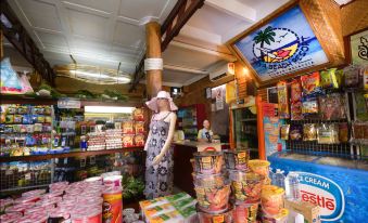 a woman wearing a hat is standing in front of a store filled with various items at Paya Beach Spa & Dive Resort