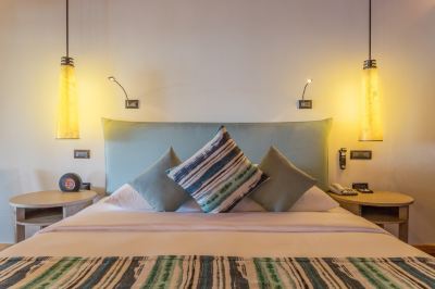 a bed with a blue headboard and two lamps on either side of the bed at Vilamendhoo Island Resort & Spa