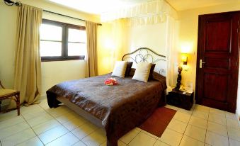 a well - decorated bedroom with a large bed , two nightstands , and a window with curtains , all decorated in warm colors at Neptune