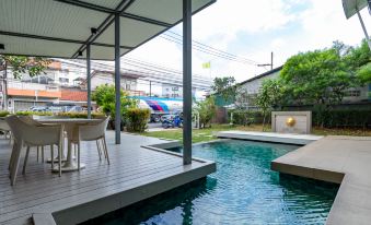 a large backyard with a pool surrounded by a wooden deck , and a dining table nearby at Viva Hotel Songkhla