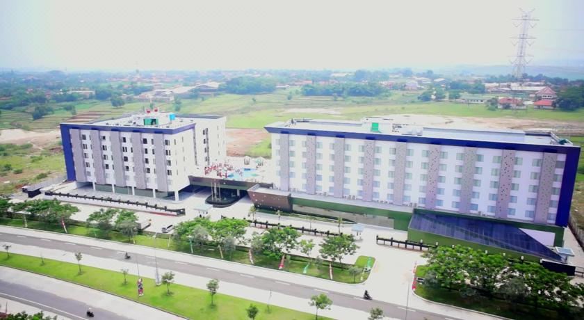 a large white building with a blue roof and green trees is surrounded by a parking lot at Sakura Park Hotel & Residence