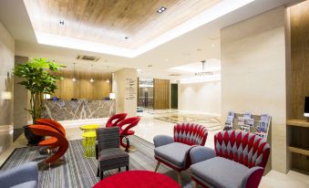 a modern lobby with a reception desk , colorful chairs , and a plant on the floor at Polaris Hotel