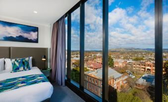 a hotel room with a large window overlooking a cityscape , featuring a bed and a tv at Mantra Albury Hotel