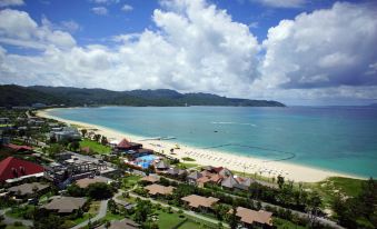 a bird 's eye view of a beach with houses , umbrellas , and people on the sand at Okuma Private Beach & Resort