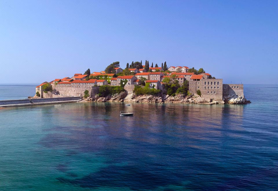 a small island with orange roofed buildings and a body of water in the background at Aman Sveti Stefan