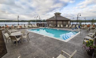 a large swimming pool with a view of the lake , surrounded by lounge chairs and tables at Chautauqua Harbor Hotel - Jamestown
