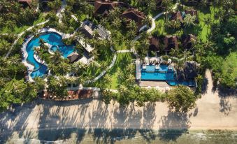 a bird 's eye view of a resort with palm trees , a pool , and a beach at Holiday Resort Lombok