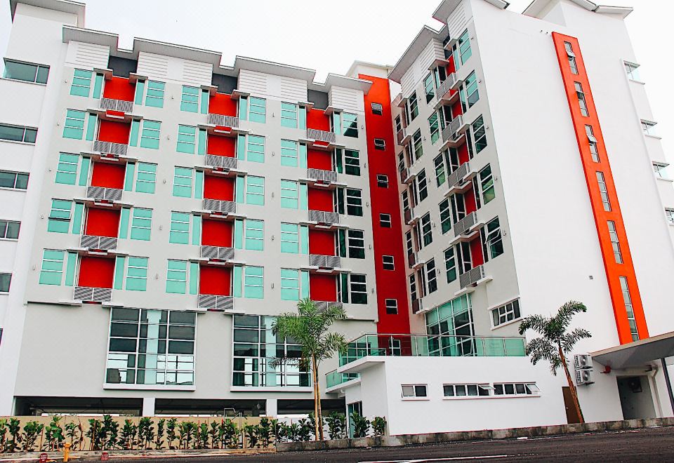 a tall , modern building with red and white accents , situated in a city setting with palm trees at 906 Premier Hotel