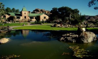 a beautiful house with a green roof is surrounded by a garden and a pond at Canyon Lodge