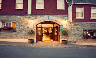 an old brick building with a red brick wall , lit up at night , and a doorway leading into the restaurant at Breffni Arms Hotel