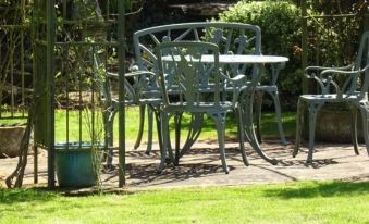 a garden table and chairs are set up in a shaded area surrounded by greenery at Moor Court Farm
