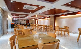 a large , empty dining room with wooden tables and chairs , red walls , and recessed lighting at Good Hotel (Beijing East Road Gaoxin Avenue Subway Station)