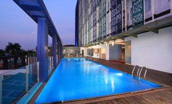 an outdoor swimming pool surrounded by a building , with a beautiful view of the city in the background at Swiss-Belinn Modern Cikande
