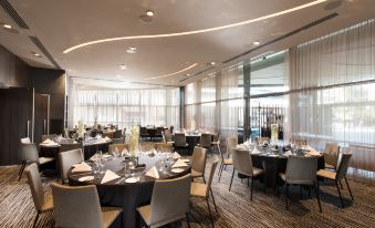 a large , well - lit banquet hall with numerous tables and chairs set up for a formal event at Pan Pacific Melbourne