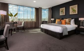 a hotel room with a king - sized bed , a desk , and a large window overlooking the city at Springfield Lakes Boutique Hotel