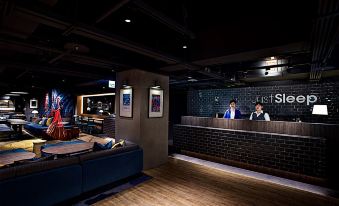 a modern office space with a black brick wall , wooden floor , and two people behind the counter at Just Sleep Ximending