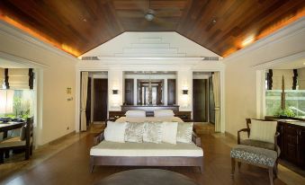 a luxurious bedroom with a large bed , hardwood floors , and a chair in the corner at Robinson Khao Lak