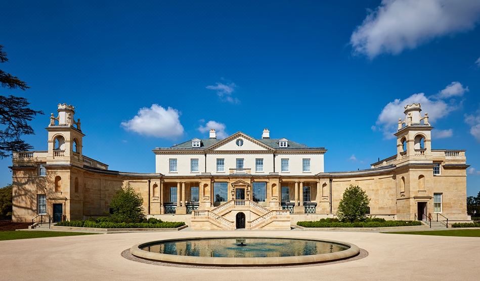 a large , white building with a pool in front of it , under a clear blue sky at The Langley, a Luxury Collection Hotel, Buckinghamshire