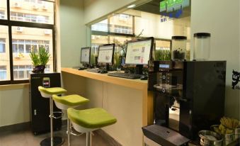 The restaurant's counter is filled with stools, tables, and chairs at Qiyou Capsule Youth Hostel