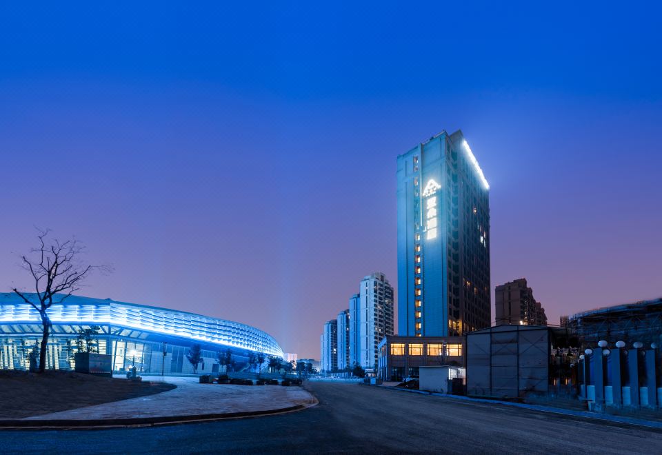 a city skyline at night , with tall buildings lit up in various colors and illuminated at Atour Hotel