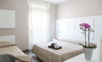 a hotel room with a white bed , curtains , and a window , along with a small table in the middle of the room at PRIMAVERA