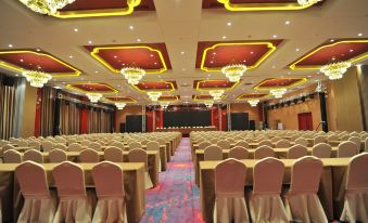 a large conference room with rows of chairs and tables , a stage at the end , and chandeliers hanging from the ceiling at Ximei Lucky Hotel