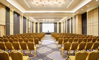 a large conference room with rows of chairs arranged in a semicircle , and a projector on the wall at Ibis Styles Bekasi Jatibening