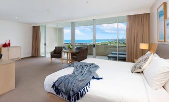 a spacious bedroom with a large window overlooking the ocean , creating a serene and inviting atmosphere at Sage Hotel Wollongong