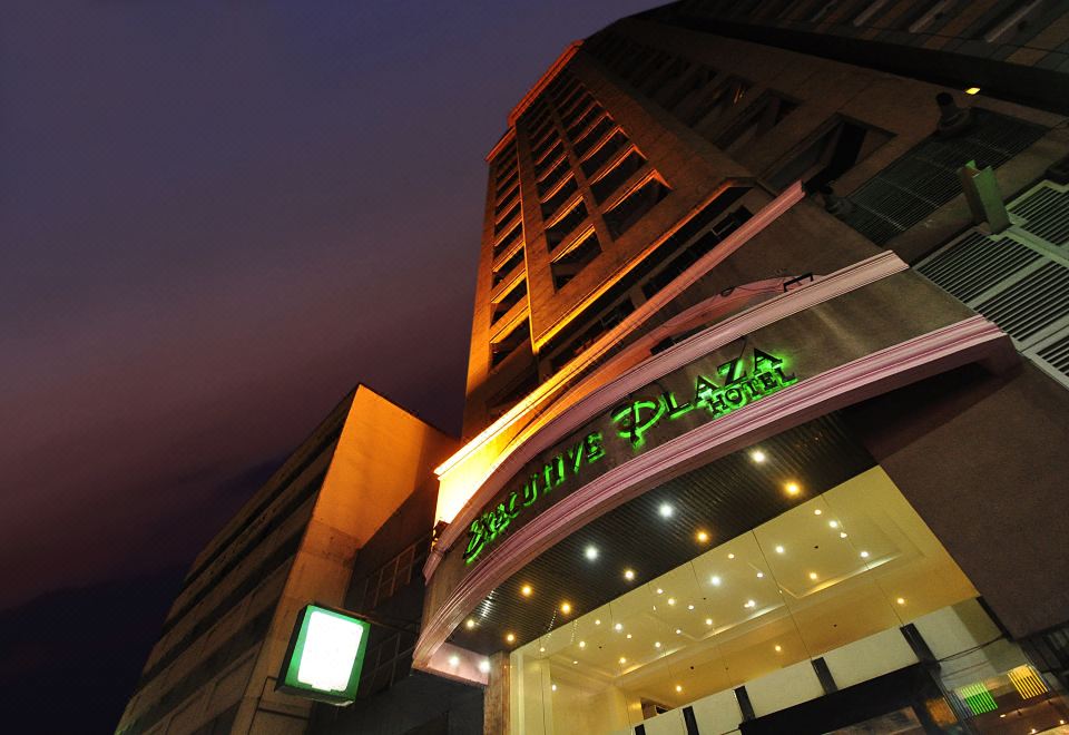 a large hotel building with multiple buildings , some of which are lit up at night at Executive Hotel