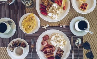 a table is set with a variety of breakfast foods , including eggs , sausage , and waffles at Bluewater Sumilon Island Resort