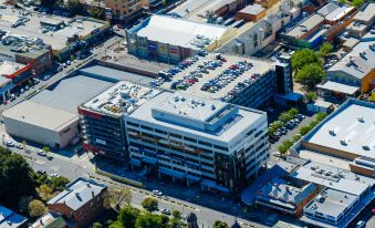 aerial view of a large building surrounded by buildings and trees , with several cars parked in the lot at Mantra Albury Hotel