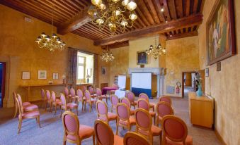 a conference room with wooden ceiling , chandelier , and rows of pink chairs facing a projector screen at Hotel Golf Chateau de Chailly