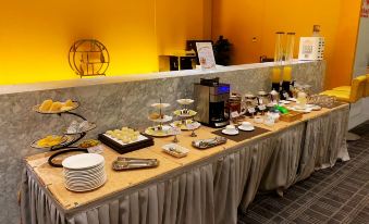 There is a table in the center with food on it, and other items are placed around it at each end at Metropolo Jinjiang Hotels (Hangzhou East Railway Station)