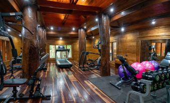 a well - equipped home gym with various exercise equipment , including treadmills and weight machines , arranged in a wooden room at Wanda Vista Resort Khum Wang Nuea • Chiang Mai