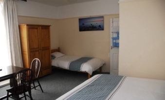 a small room with two beds , one on the left and one on the right side of the room at Prince of Wales