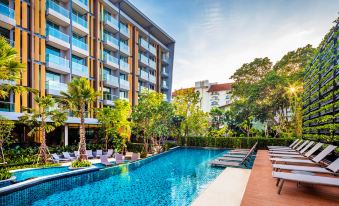 a large swimming pool with a long strip of water in front of a tall building at Hotel Amber Pattaya